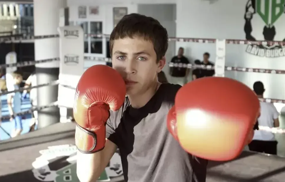 Joven púgil del Club de Boxeo David Burgos en posición de guardia con guantes rojos sobre el ring