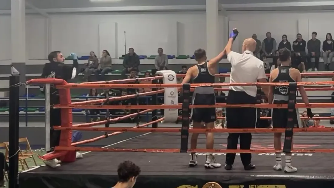 El árbitro levanta el brazo del ganador en el ring del II Open Futuros Campeones, con el público en las gradas