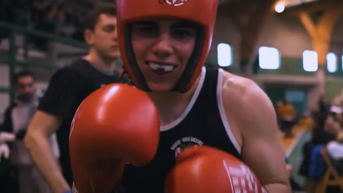 Boxeador del club con casco rojo, protector bucal y guantes en guardia antes de su combate en el Open de Marín