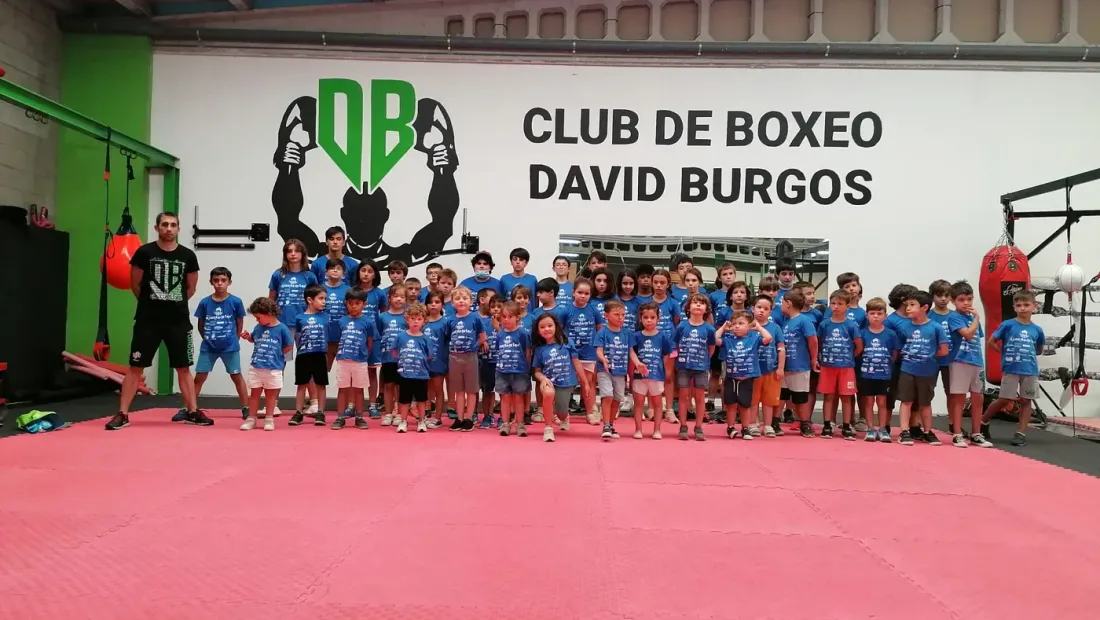 Los niños del campamento Casiña de Teo posando en grupo bajo el logo del Club de Boxeo David Burgos