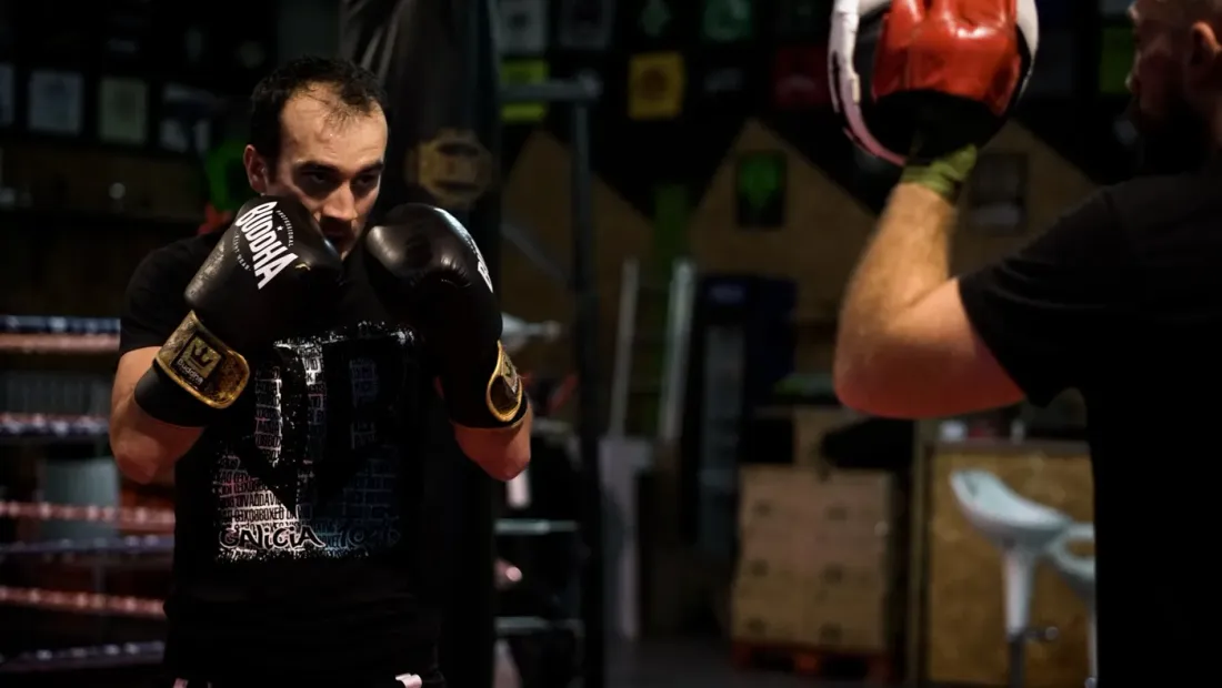 Boxeador del club golpeando las manoplas de su entrenador durante el calentamiento previo a la velada