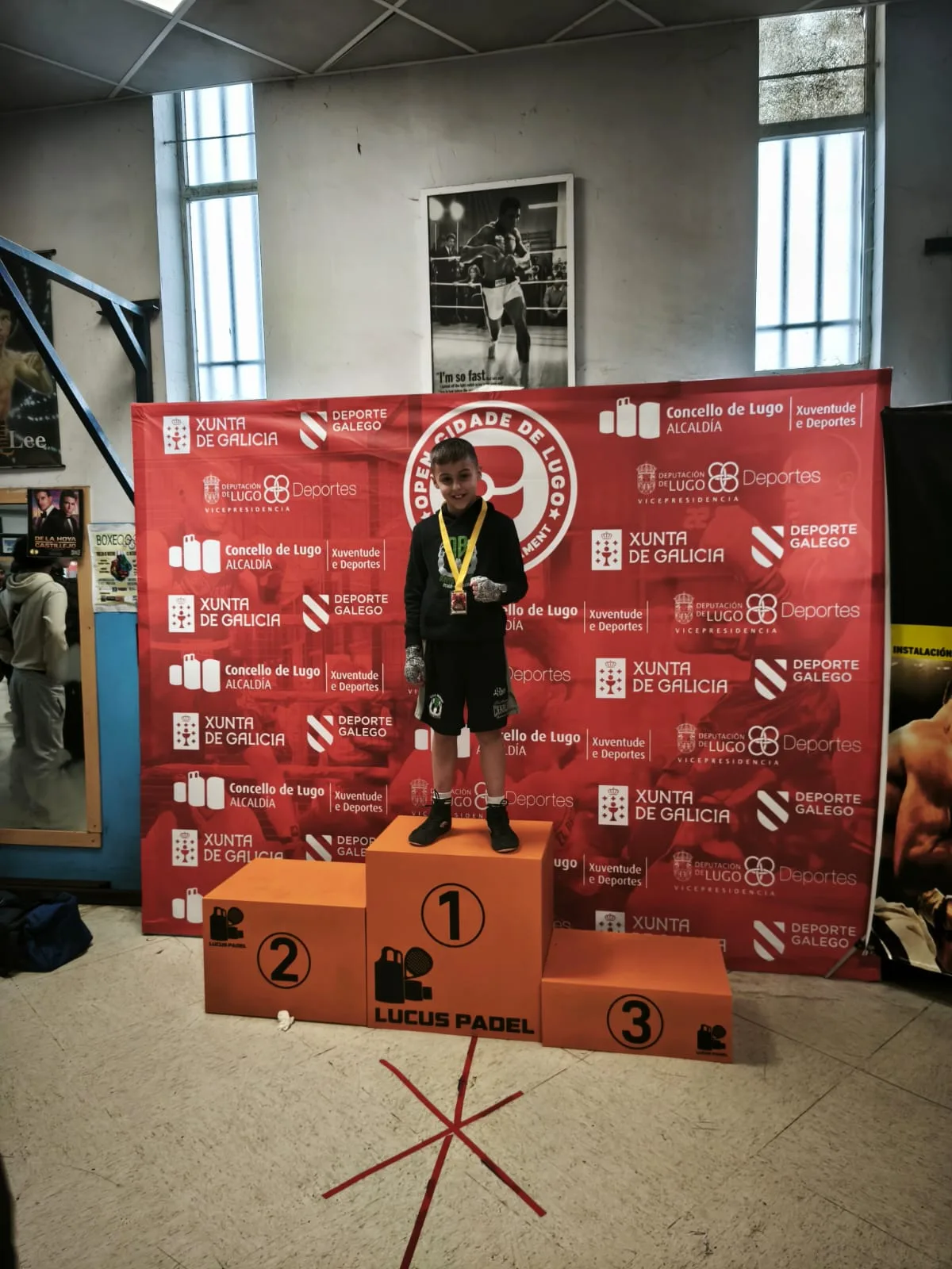 Joven boxeador del club en lo alto del podio con su medalla de oro, ante el photocall del Open Cidade de Lugo