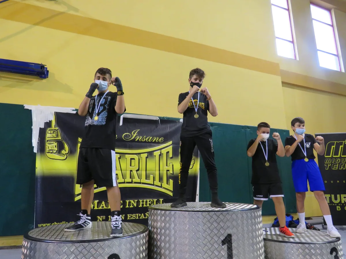 Púgiles de la cantera posando en guardia en el podio de la Copa Diputación ante el cartel de la organización